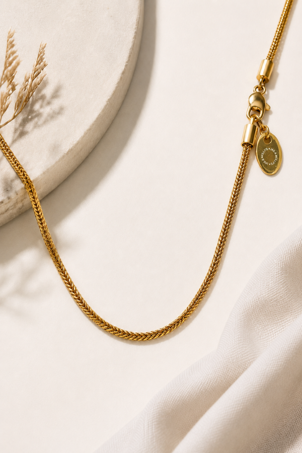 Gold Franco chain necklace styled on a warm neutral background with linen and natural accents