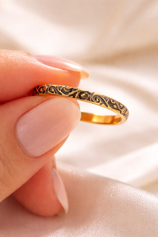 Black enamel filigree 18k PVD gold plated stainless steel band ring held between fingers close up detail texture
