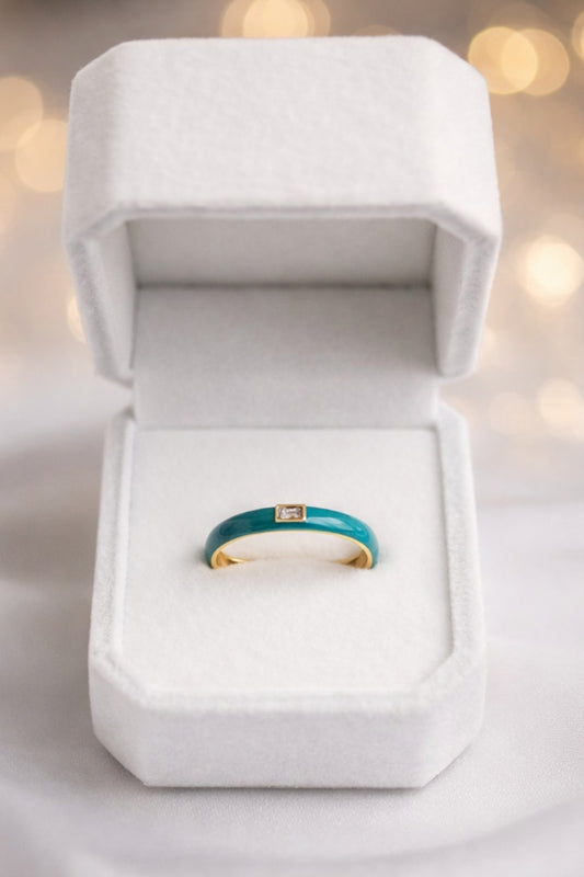 teal enamel gold band ring with baguette stone centered in white jewelry box display