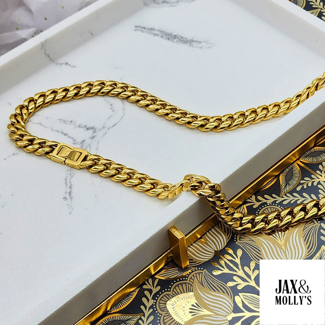 Gorgeous sparkling gold cuban link necklace displayed on a white marble jewelry holder.