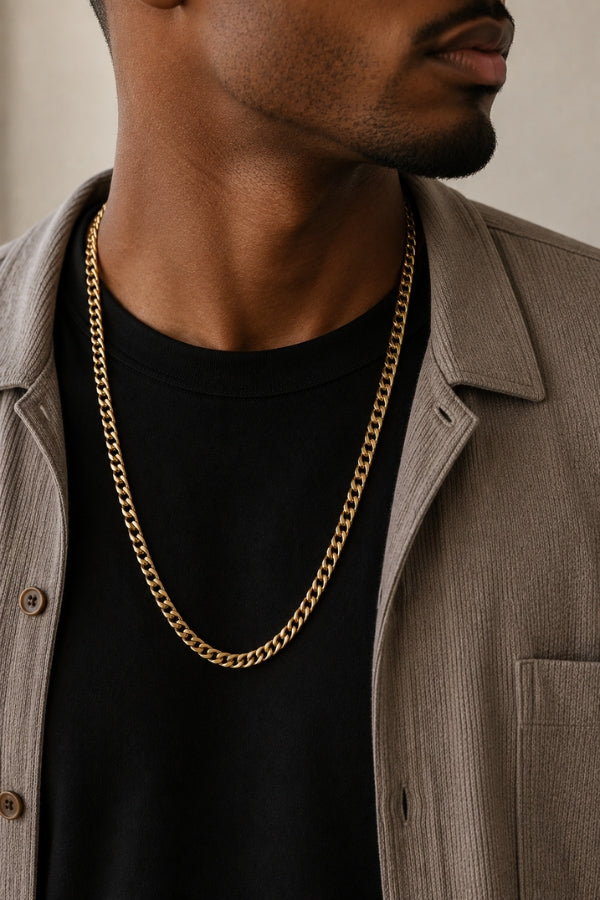Close-up of a man wearing the 8mm Cuban Link 18K Gold PVD Necklace with a black t-shirt and taupe overshirt.