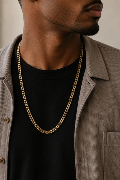 Close-up of a man wearing the 8mm Cuban Link 18K Gold PVD Necklace with a black t-shirt and taupe overshirt.