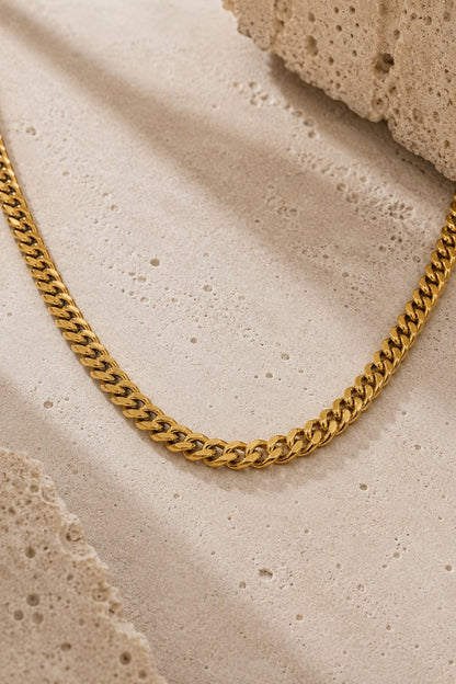 Close-up of the 8mm Cuban Link 18K Gold PVD Cuban link necklace on a neutral stone background, highlighting the polished links and premium finish.