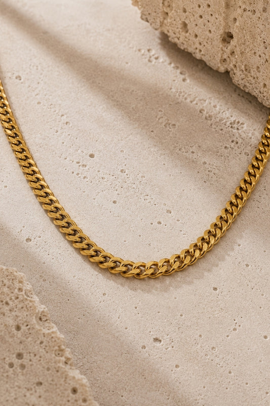 Close-up of the 8mm Cuban Link 18K Gold PVD Cuban link necklace on a neutral stone background, highlighting the polished links and premium finish.