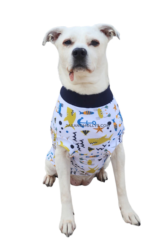 Medium white dog wearing sea creature print dog pajamas, front view showing chest fit and neckline