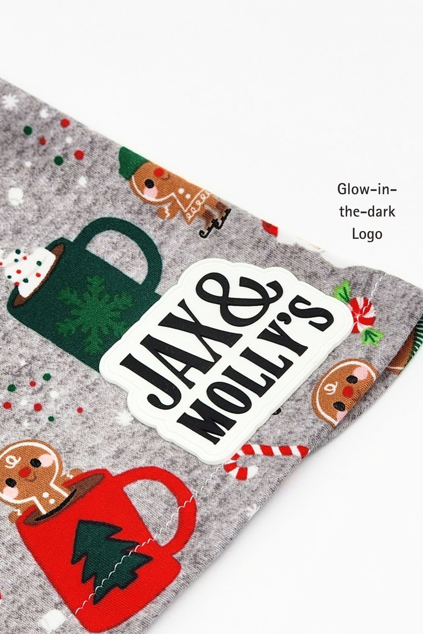 Close-up of a Glow-in-th-dark 'Jax & Molly's' label on a Christmas-themed dog pajama shirt.