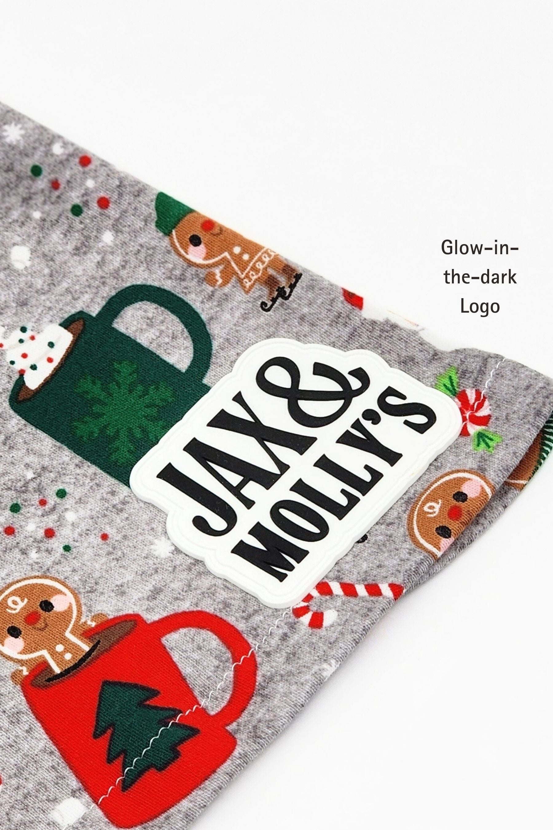 Close-up of a Glow-in-th-dark 'Jax & Molly's' label on a Christmas-themed dog pajama shirt.
