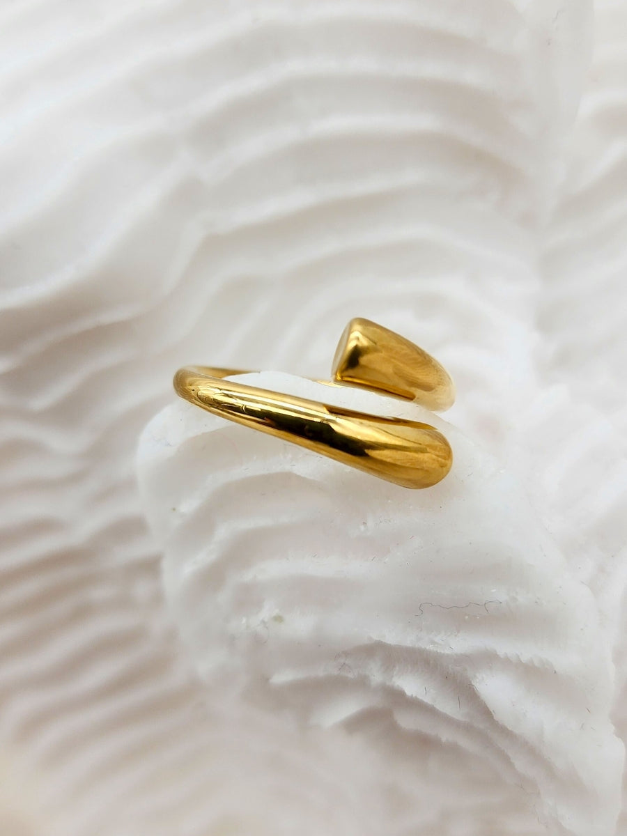 A exquisitely shiny, adjustable gold cuff ring place on white coral.