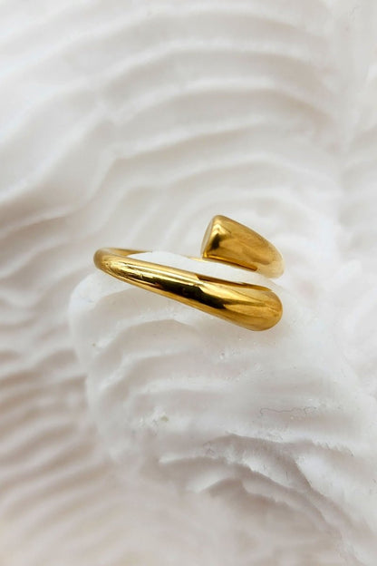 A exquisitely shiny, adjustable gold cuff ring place on white coral.