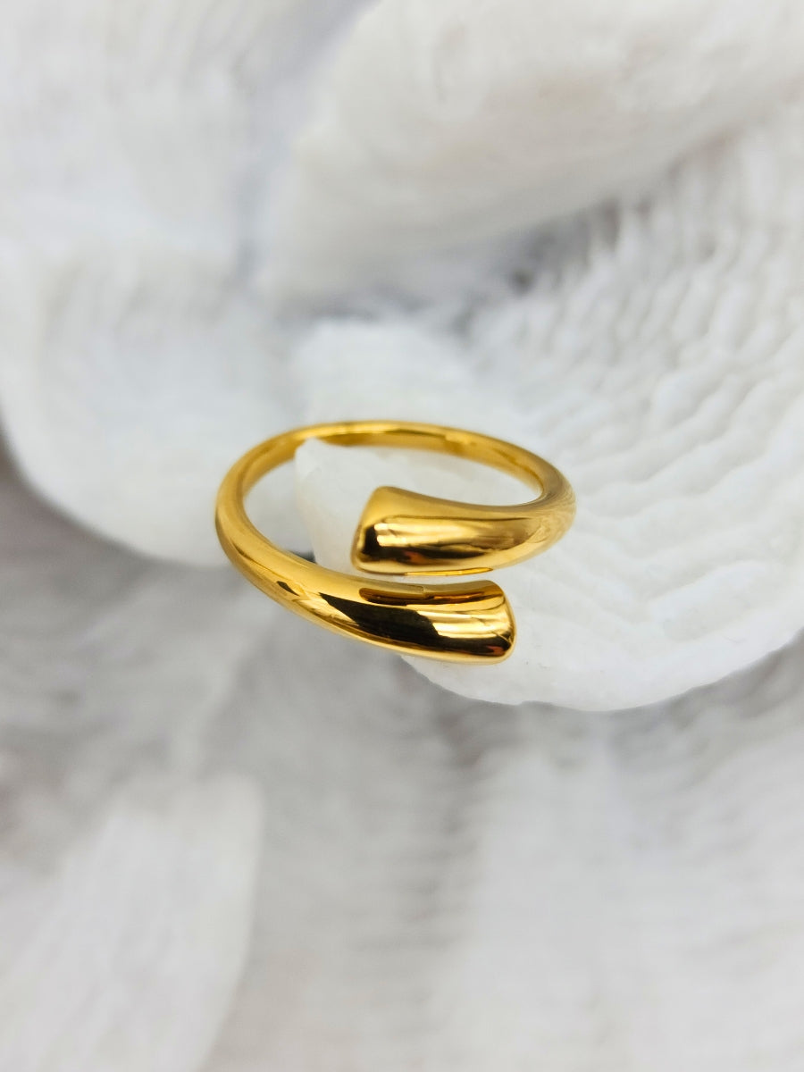 A exquisitely shiny, adjustable gold cuff ring placed on white coral.