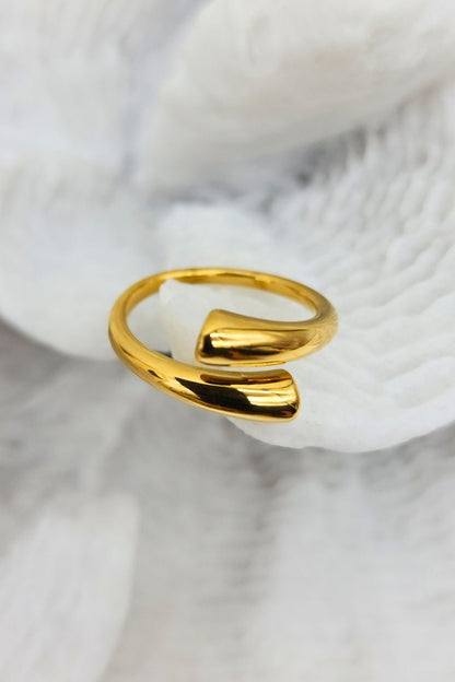 A exquisitely shiny, adjustable gold cuff ring placed on white coral.