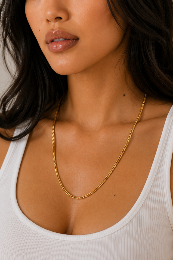 Woman wearing a gold Franco chain necklace with a polished woven link design