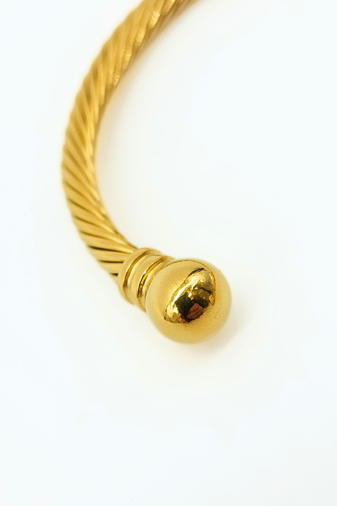 Close-up of gold rope cuff bangle adorned with decorative ball ends