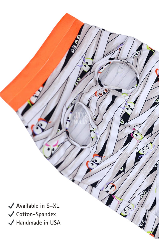 Glow-in-the-dark Halloween dog pajamas with mummy wrap print and orange trim featuring text about product details.