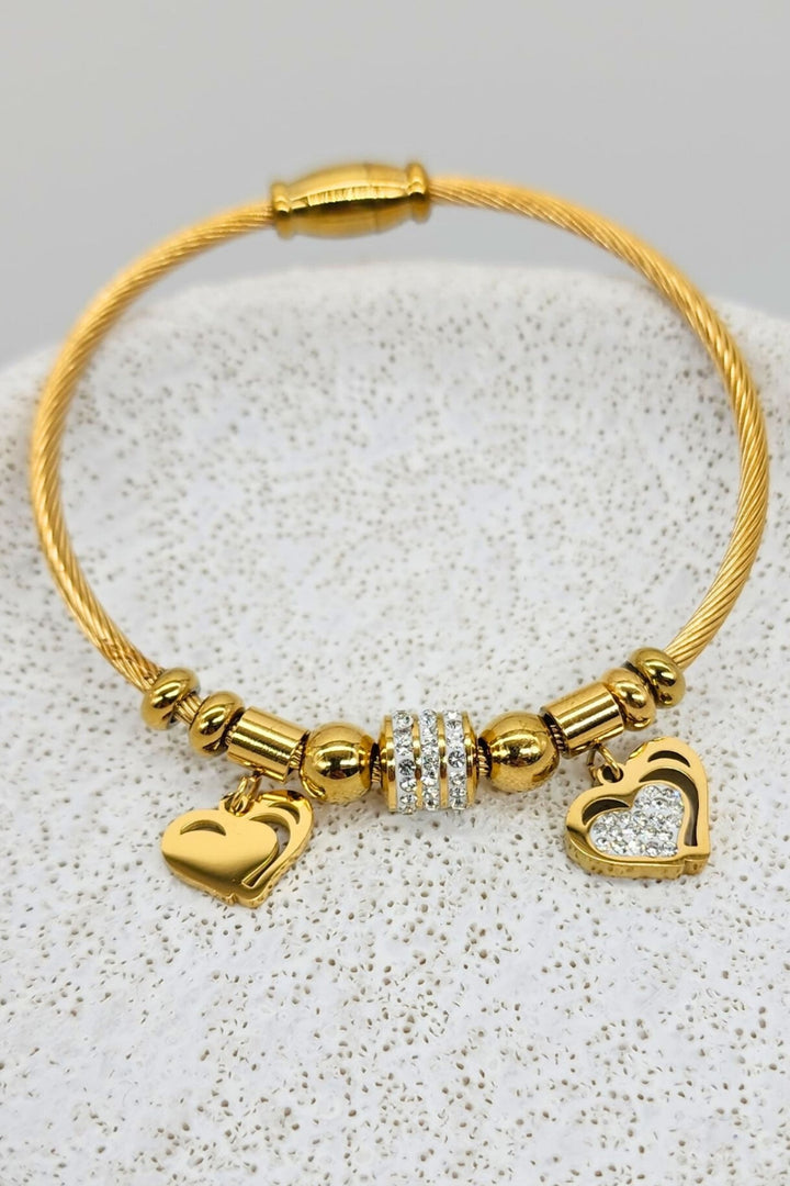 Jax & Molly's 18k gold-plated Heart Duo Bracelet featuring a cable design with two exquisite heart pendants—one embellished with sparkling crystals and the other showcasing a brilliant gold shine.