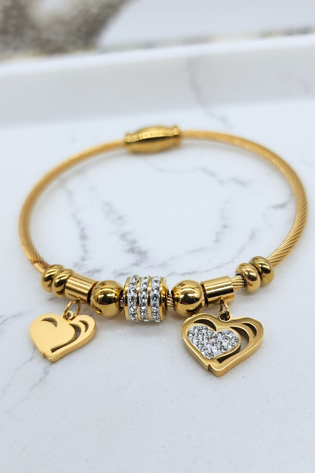 Jax & Molly's 18k gold-plated Heart Duo Bracelet featuring a cable design with two exquisite heart pendants—one embellished with sparkling crystals and the other showcasing a brilliant gold shine.