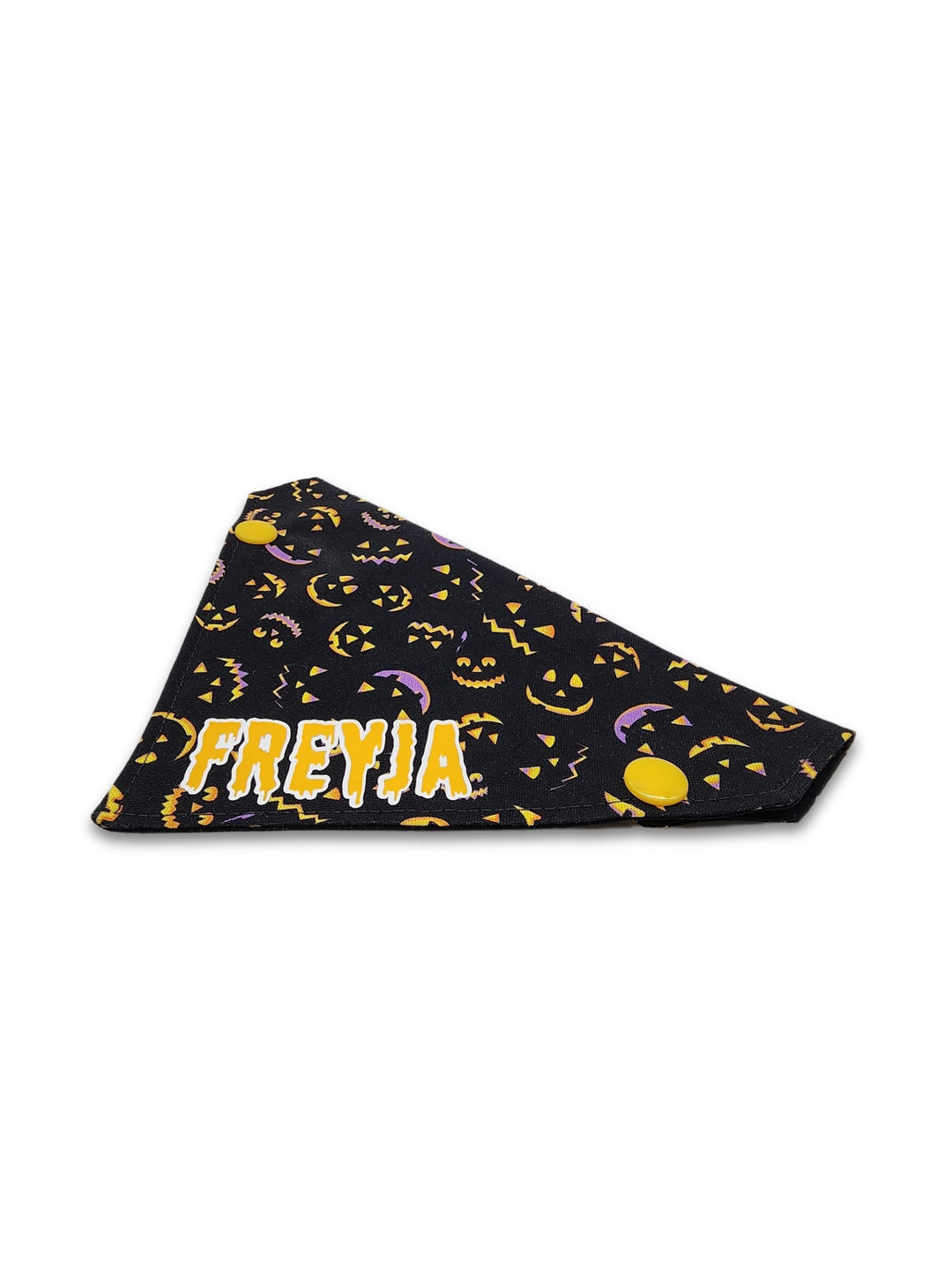 Side profile of black halloween dog bandana featuring lit up pumpkin faces and a yellow graphic that reads the name Freyja on a white background.