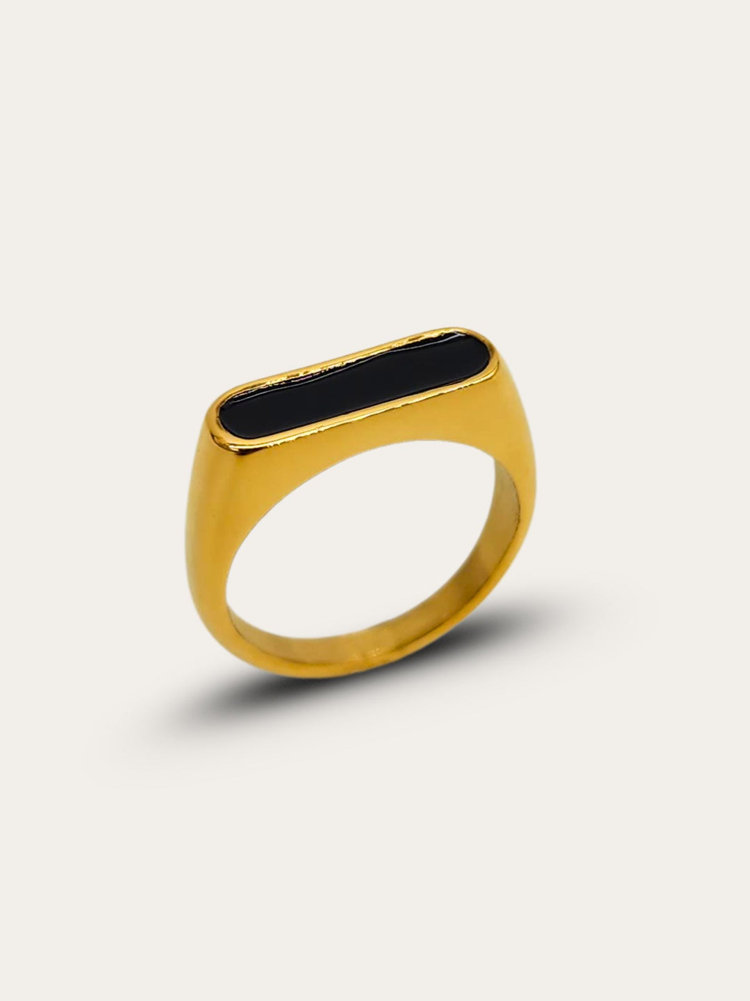 Side profile of a stunning gold ring featuring a raised oblong black enamel setting that serves as its centerpiece.