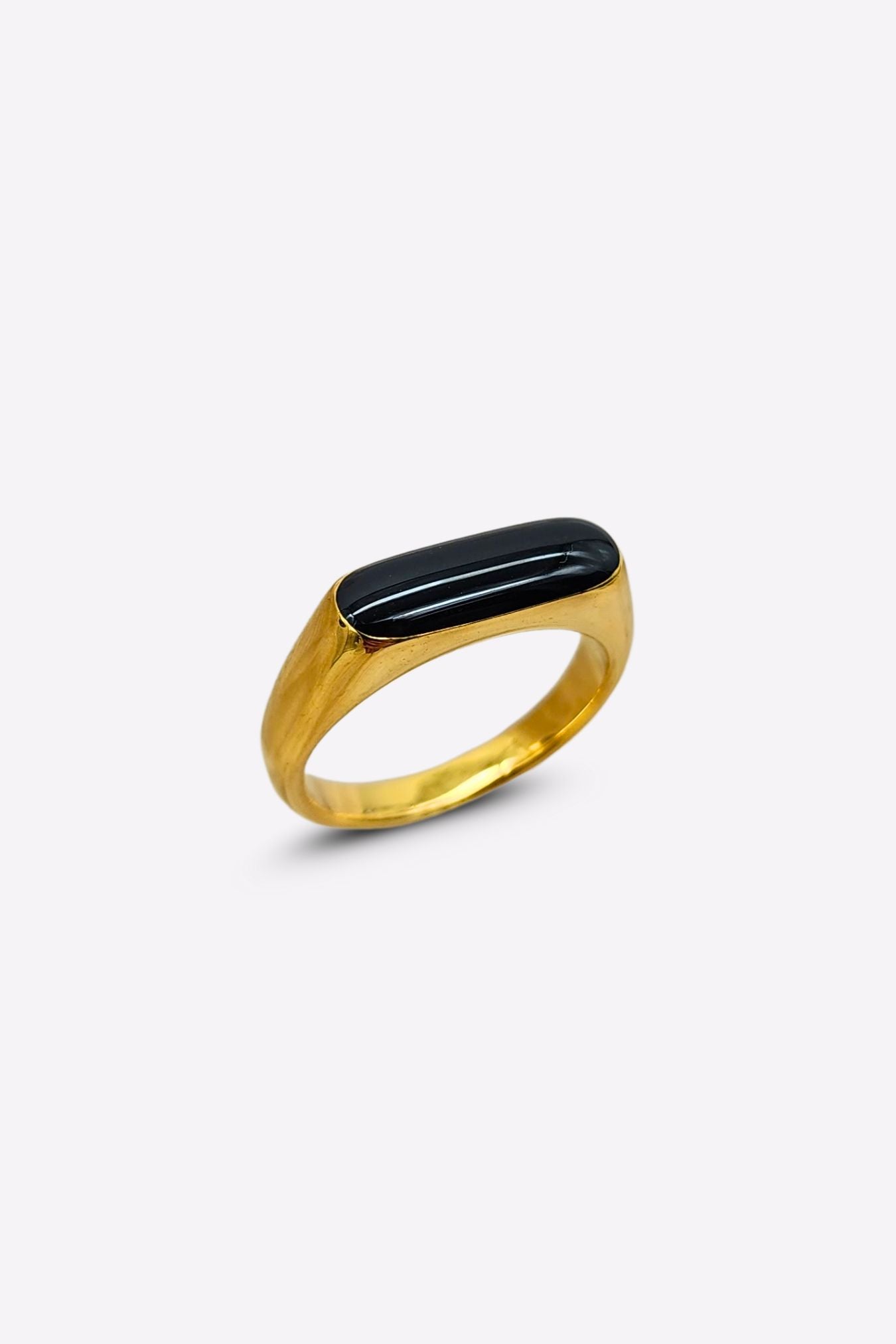 Side profile of a stunning gold ring featuring a raised oblong black enamel setting that serves as its centerpiece.