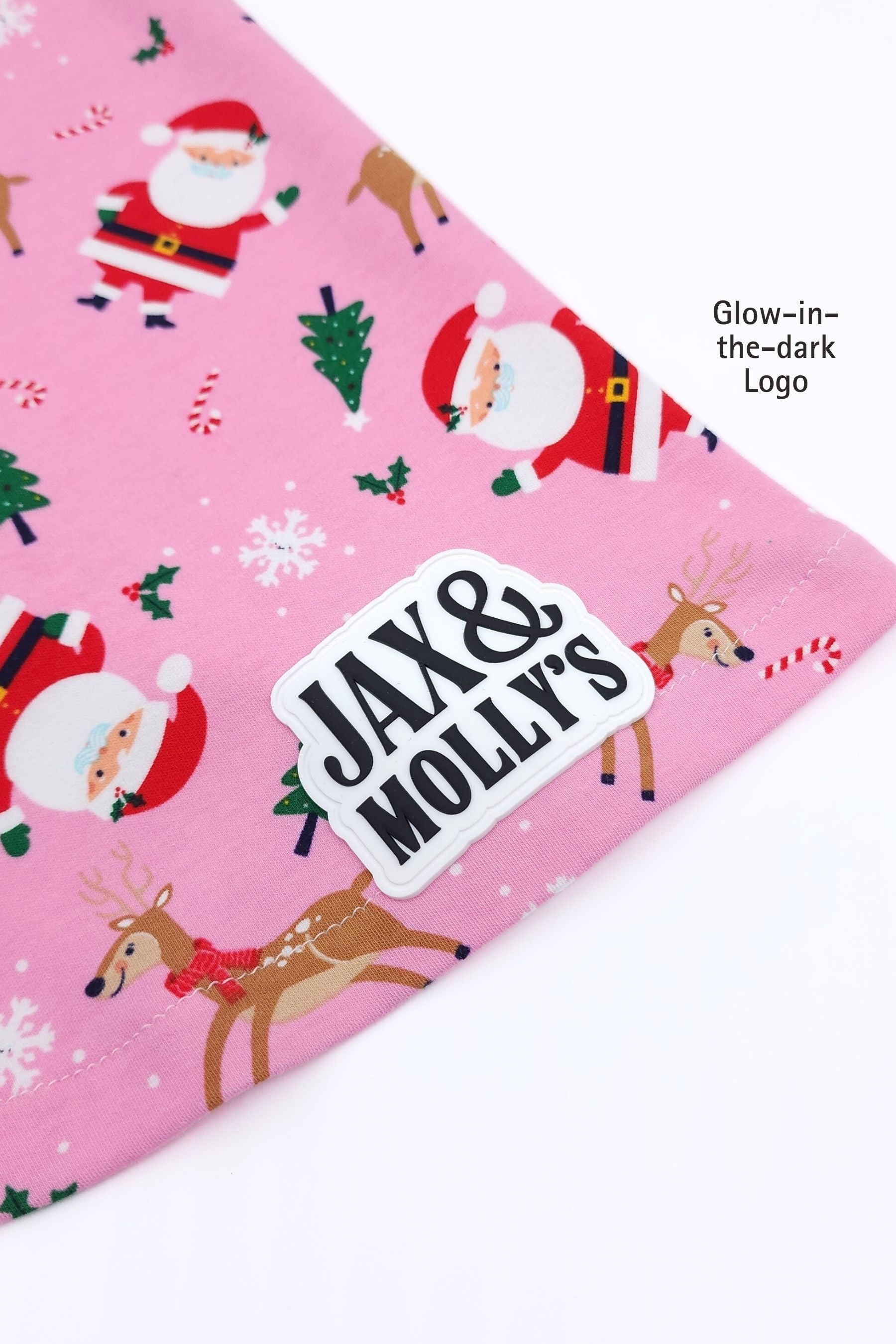 Pink fabric with Christmas-themed design featuring Santa Claus, reindeer, and snowflakes, with 'Jax & Molly's' logo.