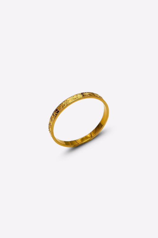 Side perspective of a gold band ring with detailed sun and ray engravings, displayed against a white backdrop.