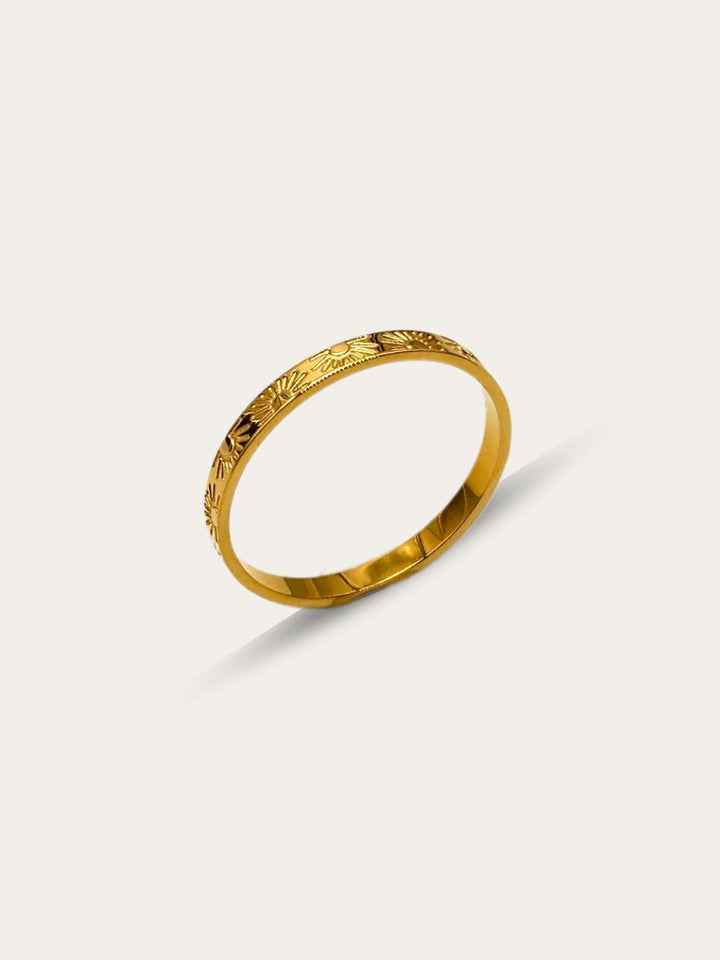 Side perspective of a gold band ring with detailed sun and ray engravings, displayed against a white backdrop.