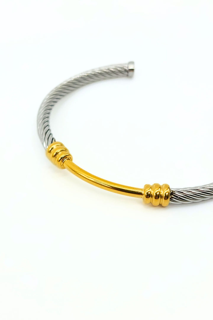 Close-up of silver and gold rope cuff bangle adorned with decorative gold middle and flat ends