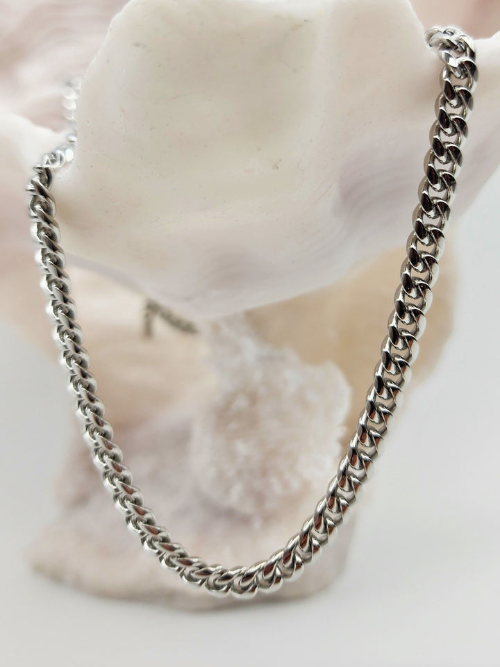 Close-up view of a 6mm silver-colored stainless steel Cuban link chain, showcasing its interlocking, polished links.