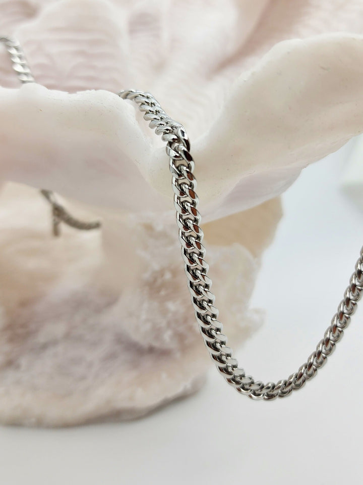 A sleek 6mm Cuban link chain in stainless steel with a silver finish, elegantly laid out to display its craftsmanship.