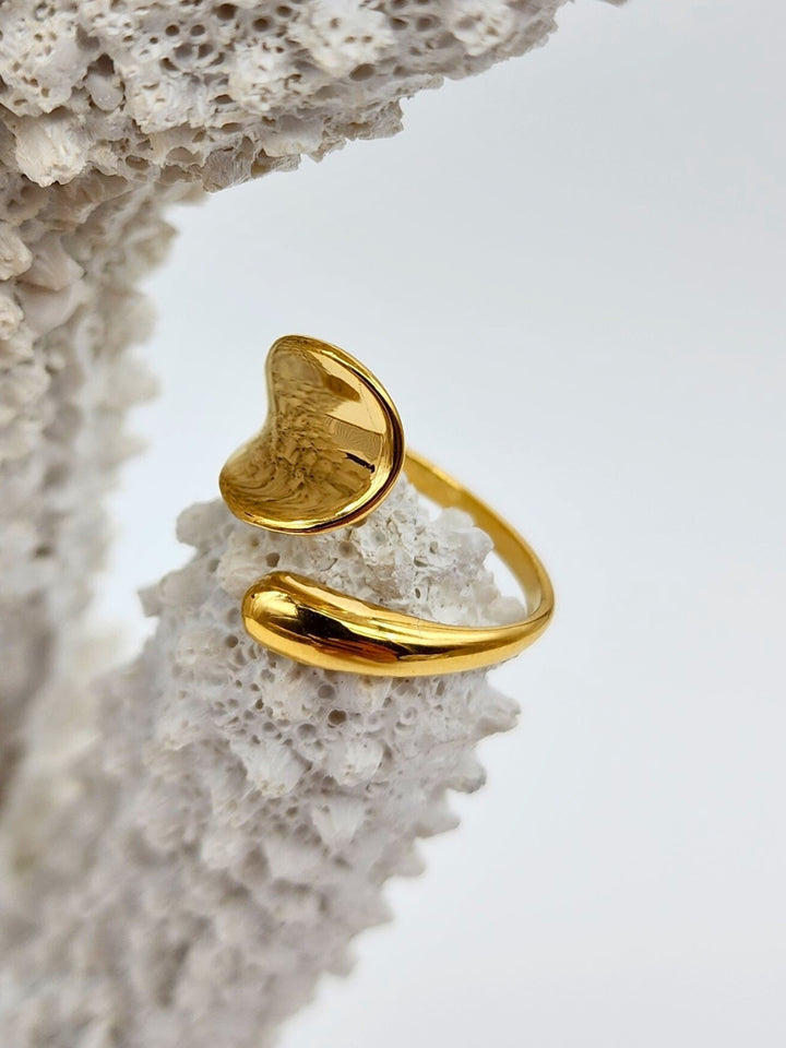 Shiny gold ring with a sleek adjustable design placed on white coral tip.