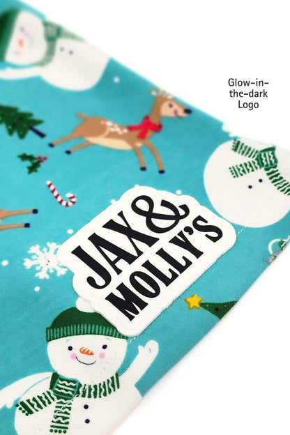 Close-up of a Glow-in-th-dark 'Jax & Molly's' label on a Snowman holiday-themed dog pajama shirt.