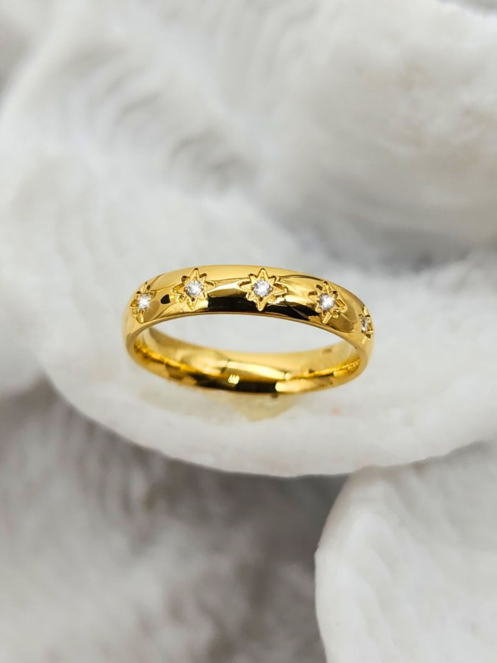 Front view of Jax & Molly's 18k PVD Gold Plated Stainless Steel Ring adorned with a Sunburst Design with Gemstones displayed on a white coral.