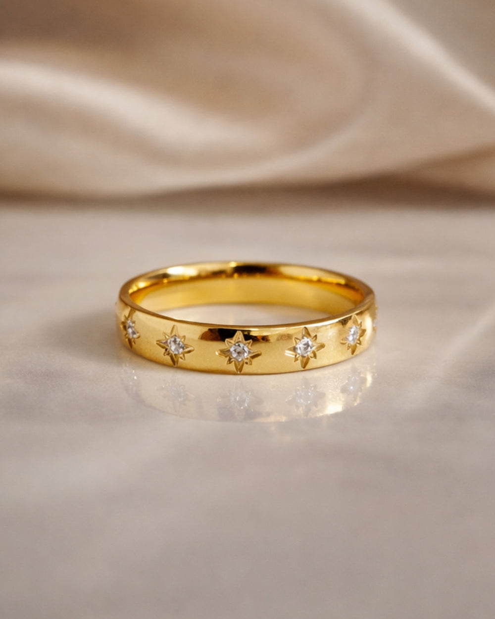 gold gemstone ring polished band sunburst star set stones flat lay marble background