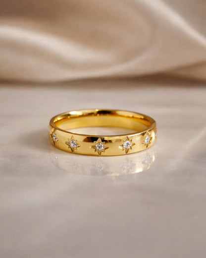 gold gemstone ring polished band sunburst star set stones flat lay marble background