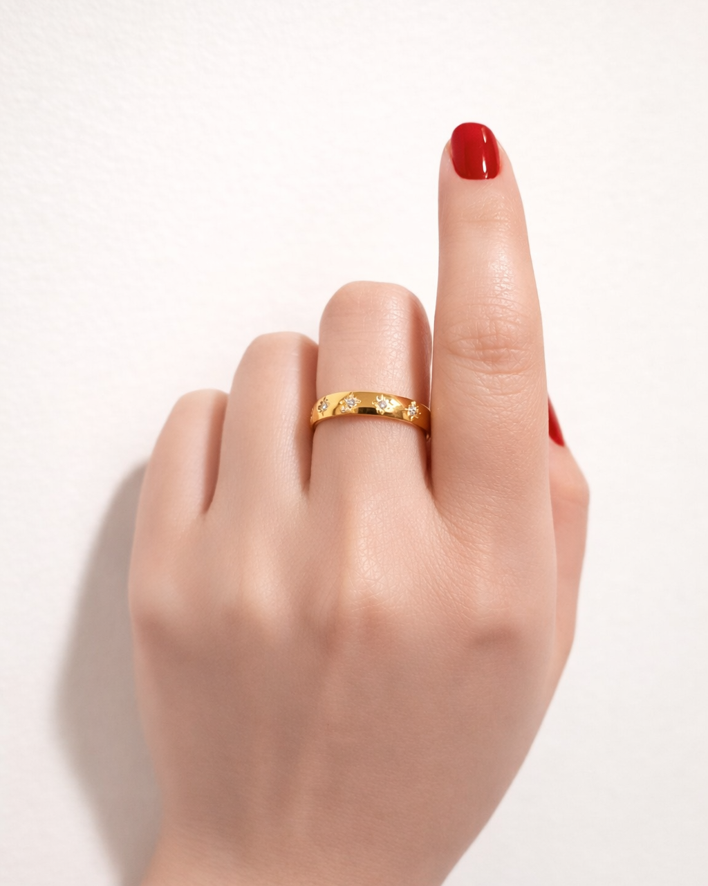 gold gemstone ring star set band on hand model red nails close up