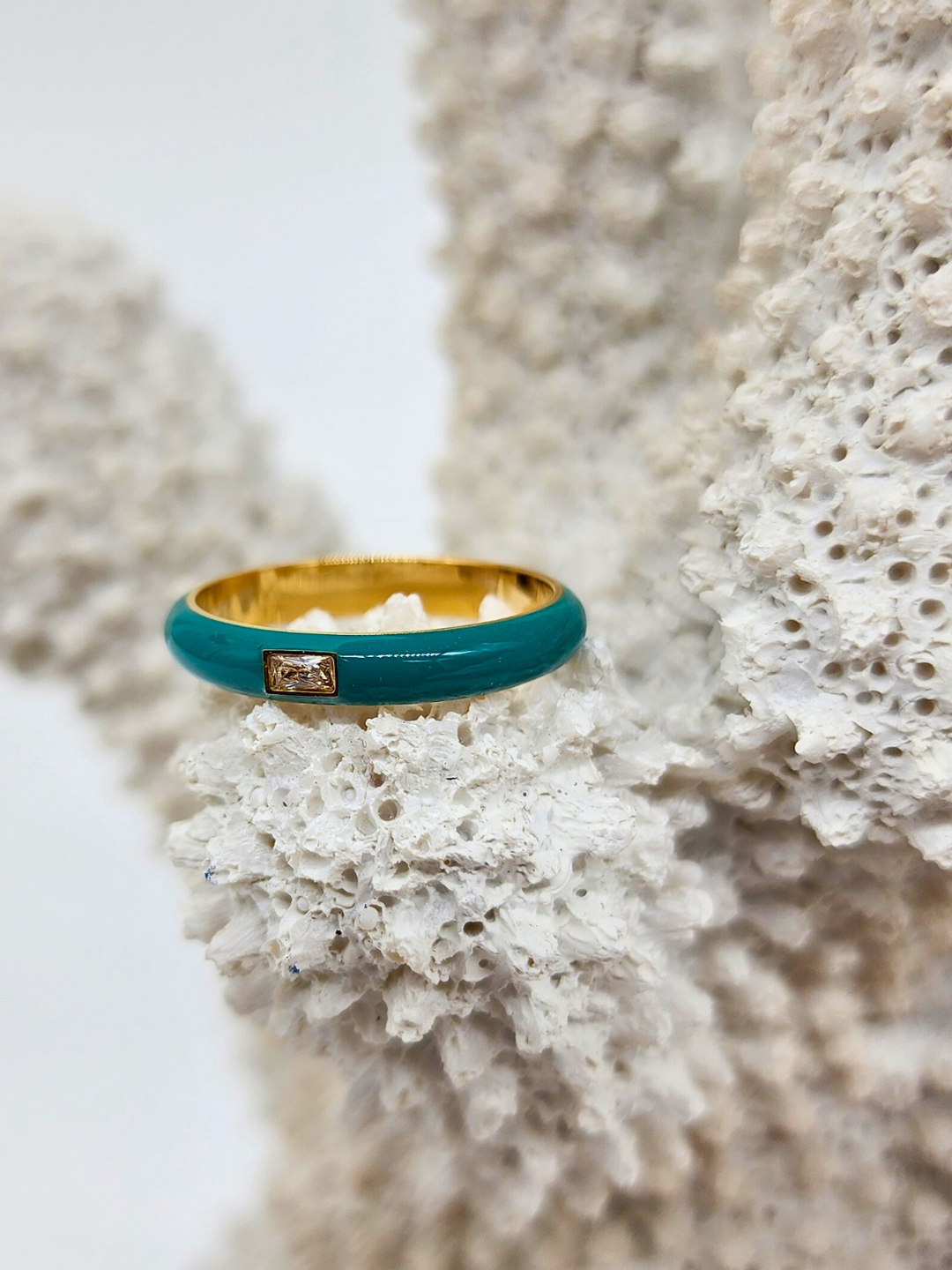 Elegant Teal Enamel Gemstone Ring displayed on white coral, capturing the harmonious blend of the teal enamel band, 18k PVD Gold Plated stainless steel, and the eye-catching rectangular gemstone.