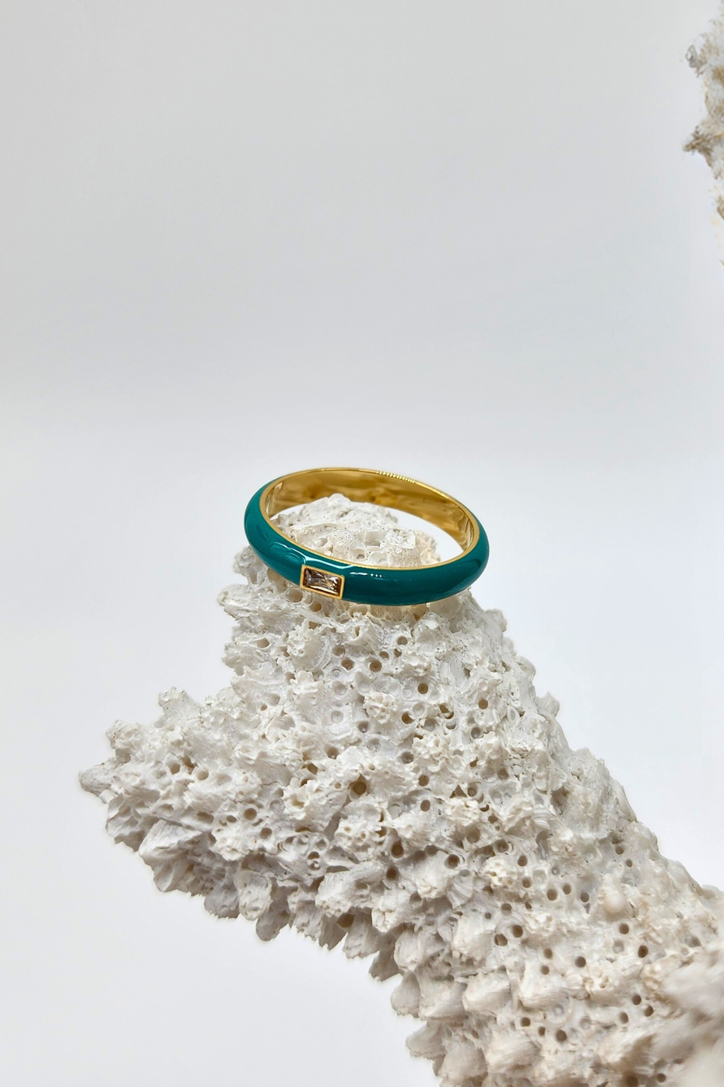 Side view of the Elegant Teal Enamel Gemstone Ring on white coral, illustrating the refined elegance of the teal enamel band and the sophistication of the rectangular gemstone set in gold-plated stainless steel.