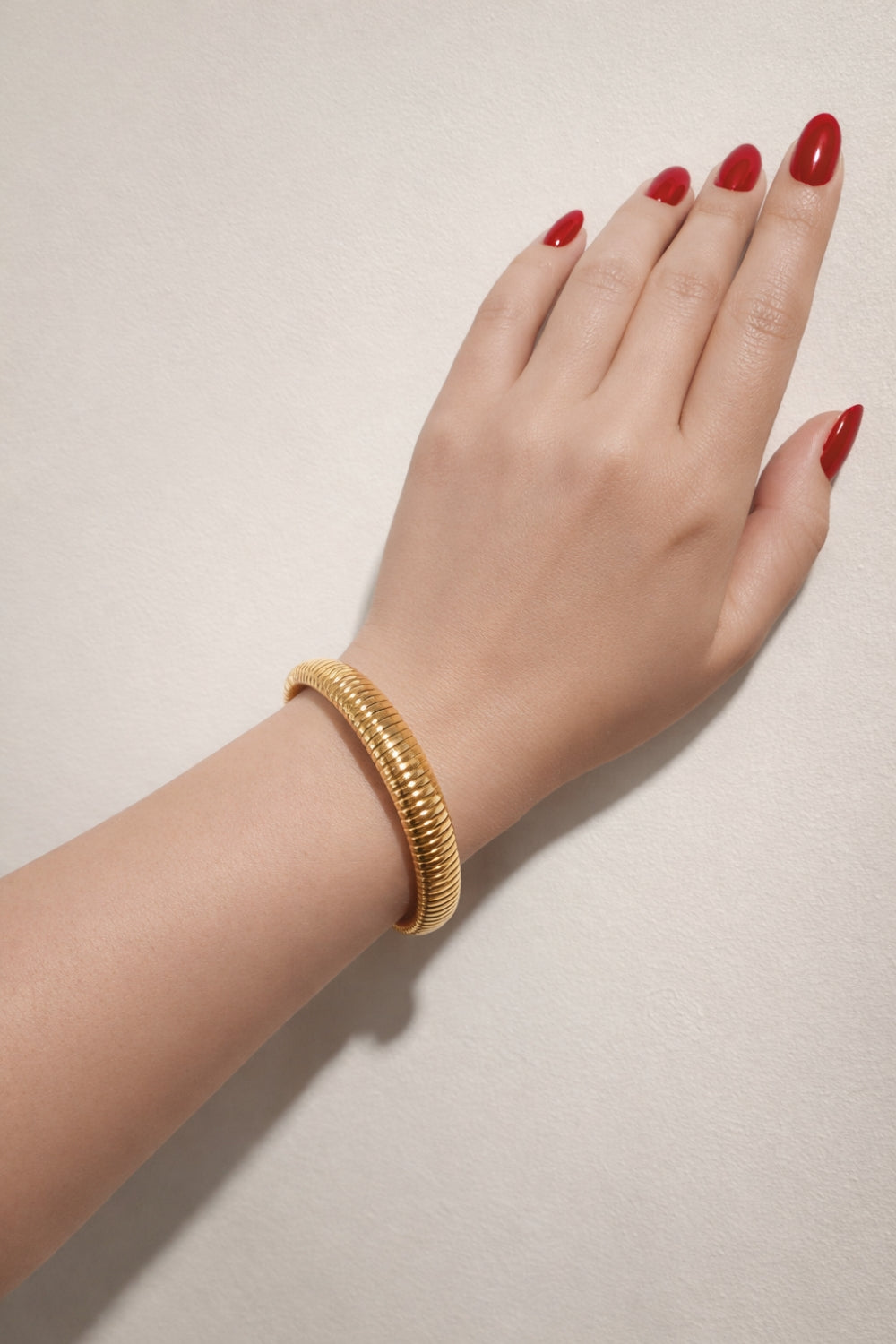 gold snake chain stainless steel bangle bracelet on wrist lifestyle view almond red nails