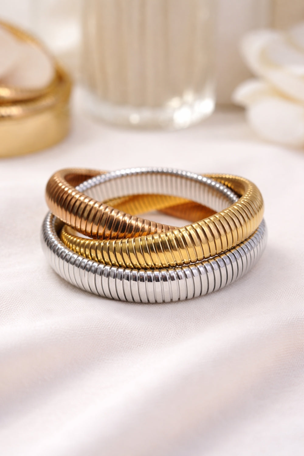 triple snake chain bracelet gold silver bronze tones stacked bangle on soft neutral fabric close-up