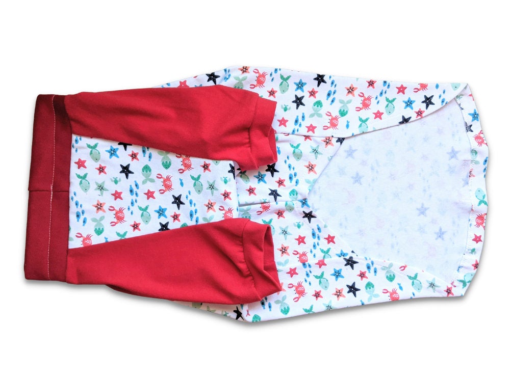 Underbelly profile of Jax & Molly's dog pajamas, decorated with sea creatures and complemented by red sleeves.
