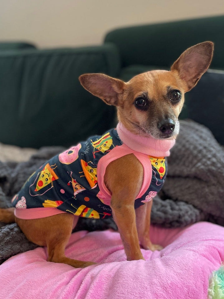 Side profile of a cute chihuahua wearing Jax & Molly's dog pajamas which showcase a unique print of animated junk foods exercising, complimented by an orange neck, sleeve and waist trim .